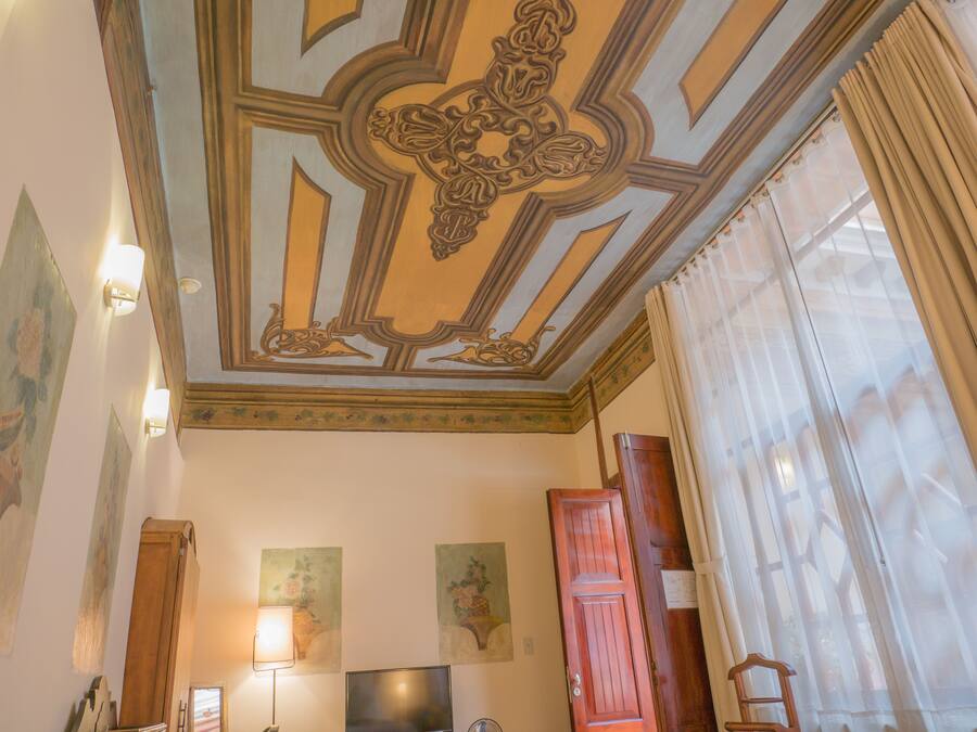 Une pièce dotée d’un plafond décoratif, d’un téléviseur à écran plat et d’une porte en bois.