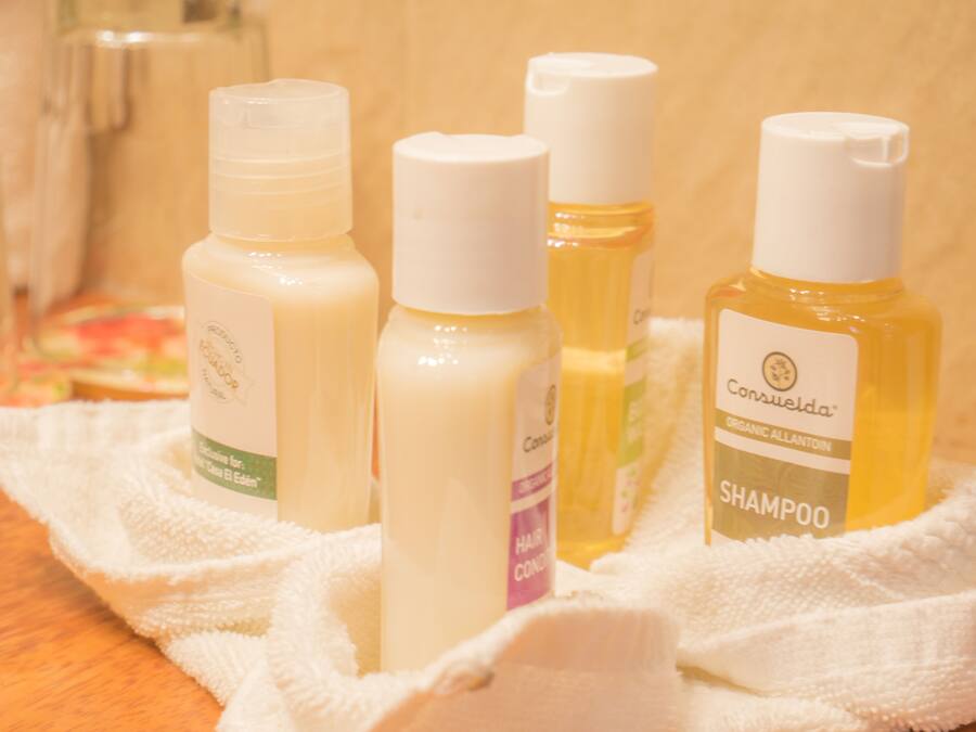 Cuatro botellas de productos para el cuidado del cabello sobre una toalla blanca.