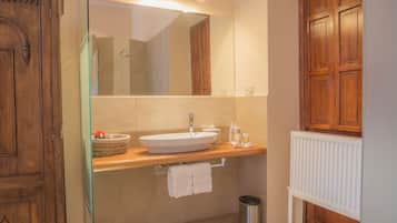 Un baño con tocador de madera, un lavabo blanco, un espejo y un radiador.