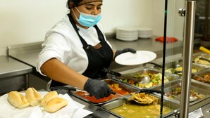 A buffet setup with various food items and a server in uniform.