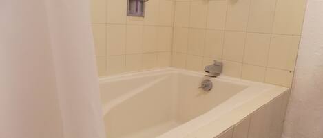 Un baño con bañera, cabezal de ducha y barra para toallas.