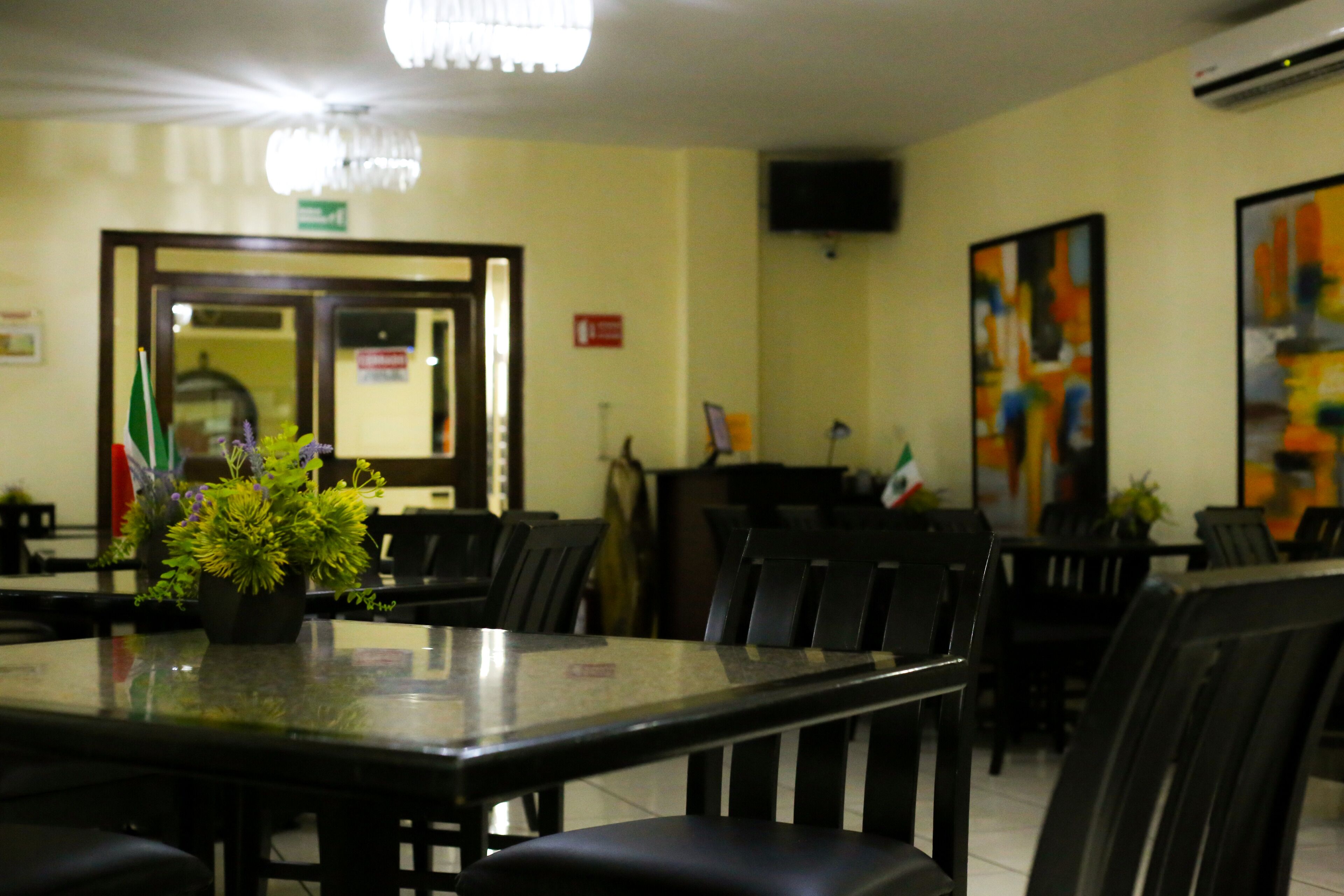 A restaurant with a long table, chairs, and a potted plant.