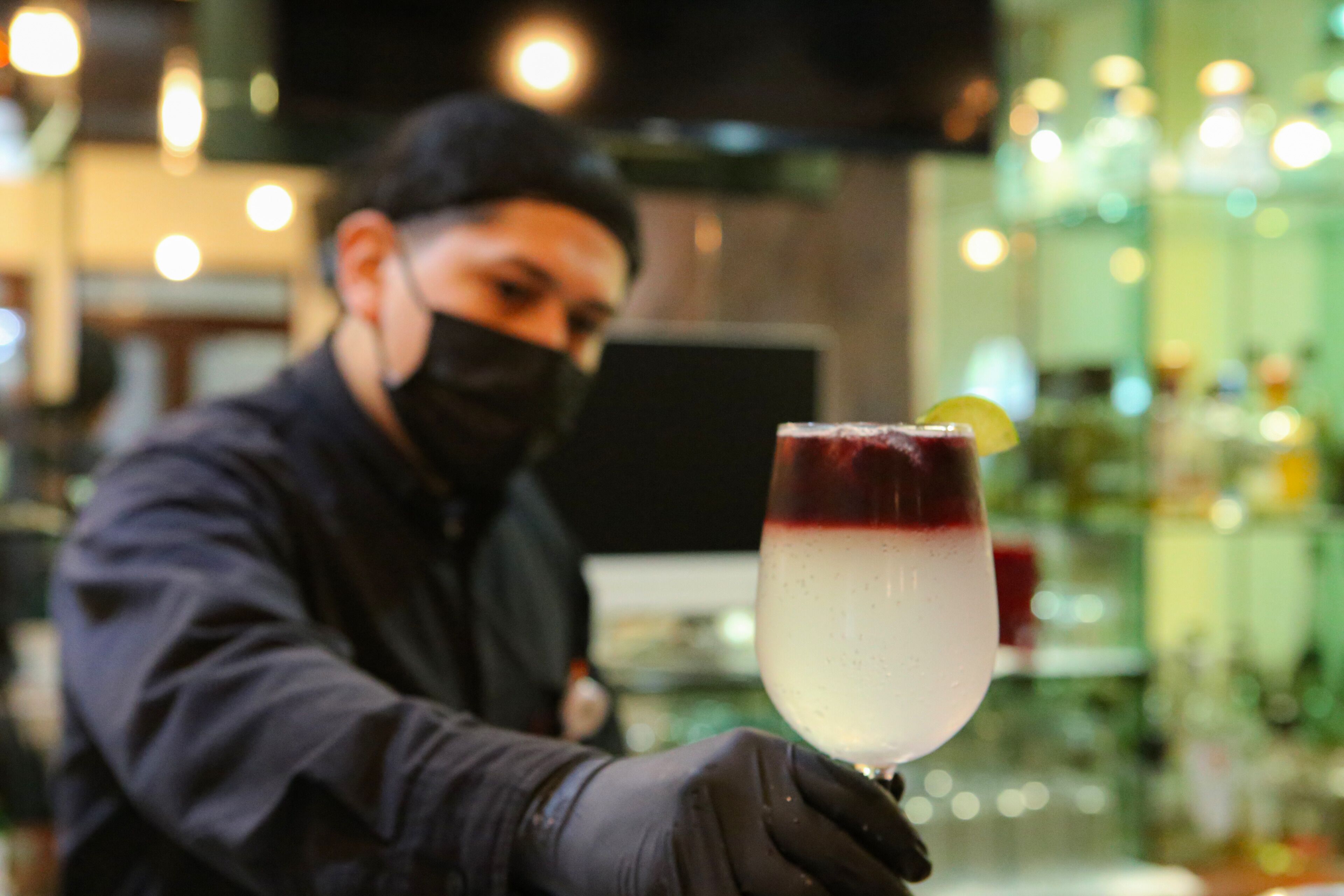 A bartender holding a cocktail glass with a lime wedge.