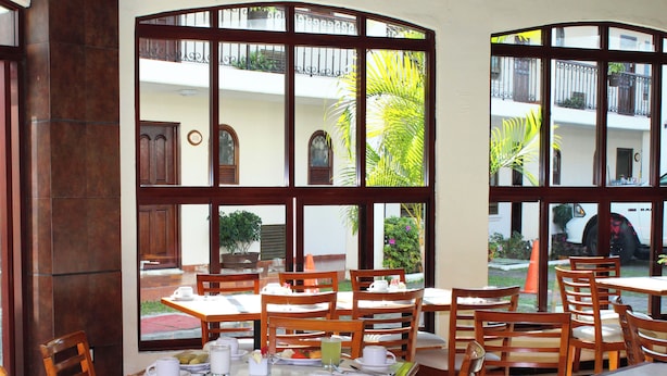 A restaurant with wooden tables and chairs, large windows with metal bars, and a view of the outside.