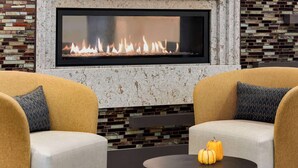 A modern living room with a large fireplace, two sofas, and a small table with pumpkins.