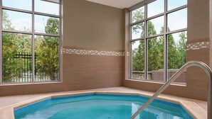 A rectangular indoor pool with clear blue water, surrounded by beige walls and a tiled border.