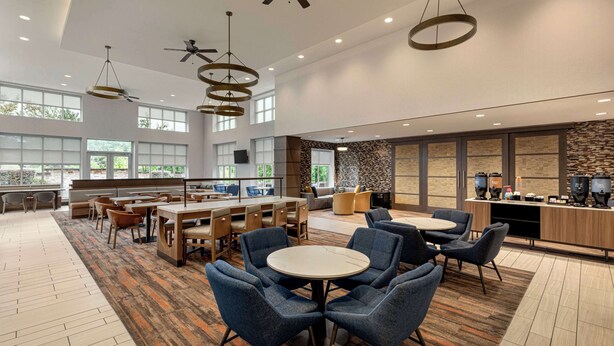 A spacious hotel lobby with high ceilings, multiple seating areas, and a central bar.