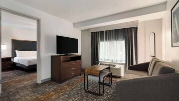 A hotel room with a bed, a TV, a desk, a chair, and a sofa.