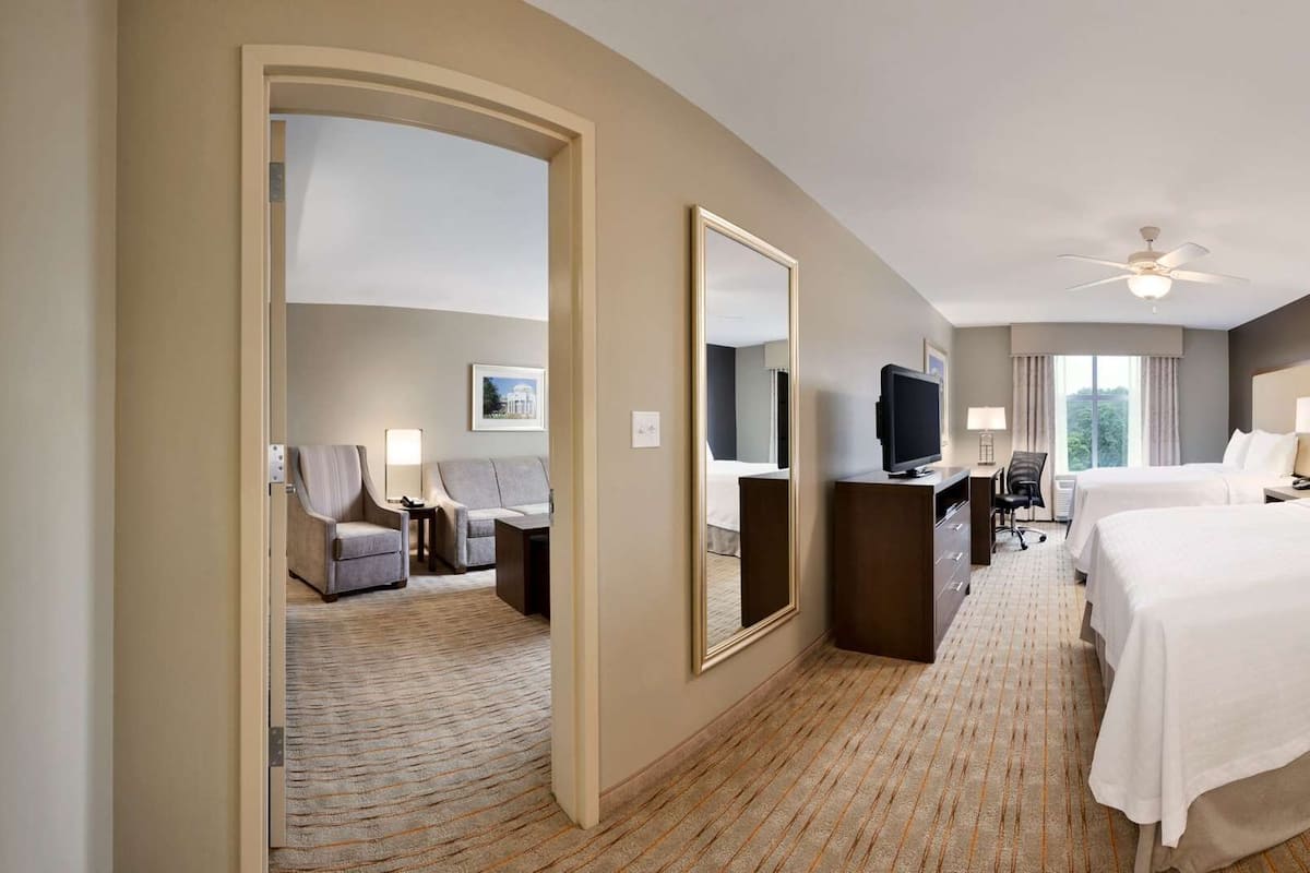 A hotel room with a bed, a sitting area, a bathroom with a shower, and a TV.
