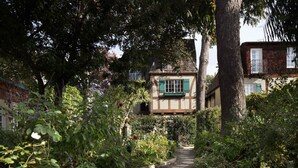 A garden pathway leading to a house with a visible window and a small balcony. - The Charlie Hotel (West Hollywood)