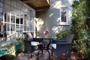 A patio with wicker chairs, a glass table, and a vase with flowers. - The Charlie Hotel (West Hollywood)