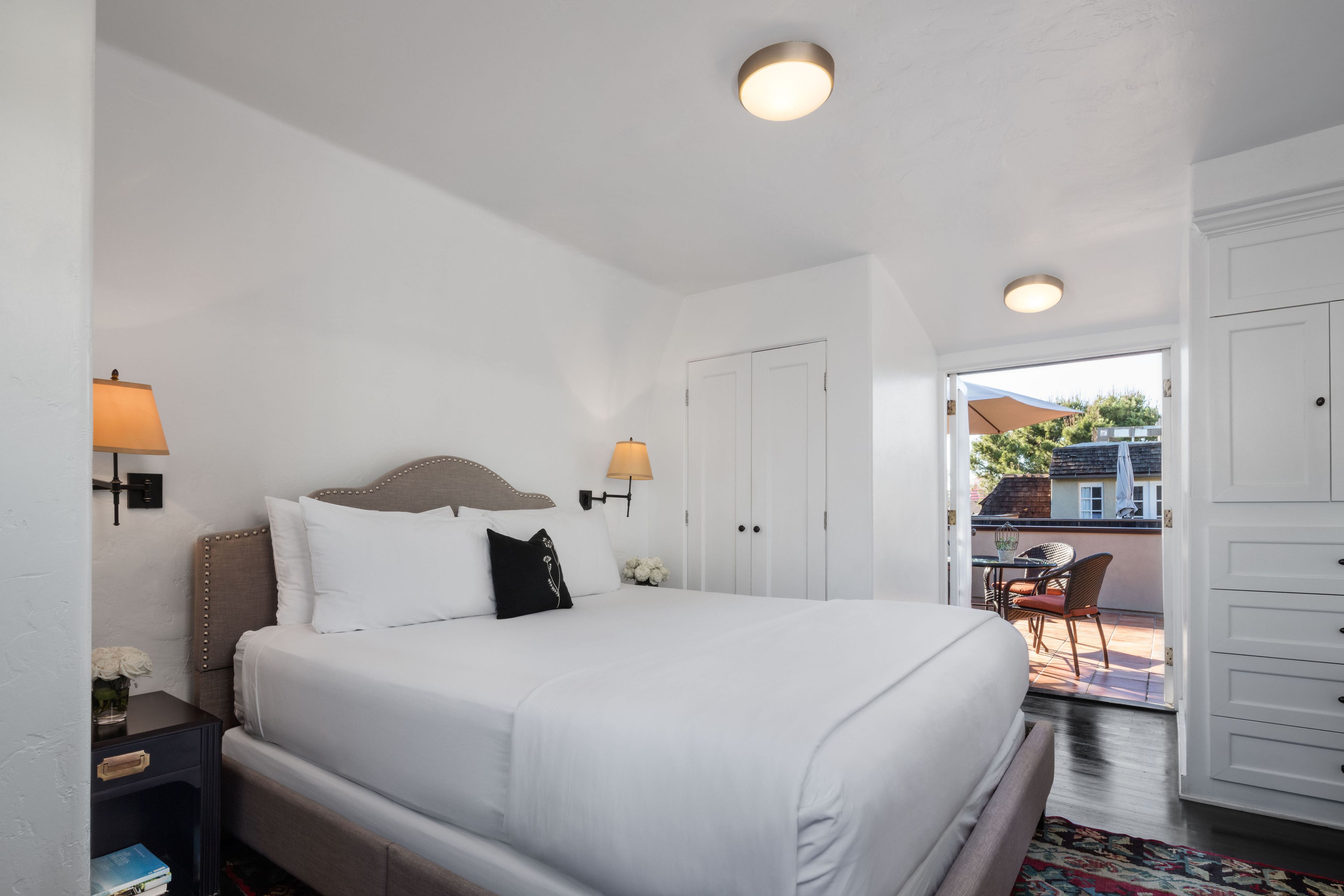 Une chambre bien rangée, avec un lit, des tables de chevet et une vue sur l’extérieur.