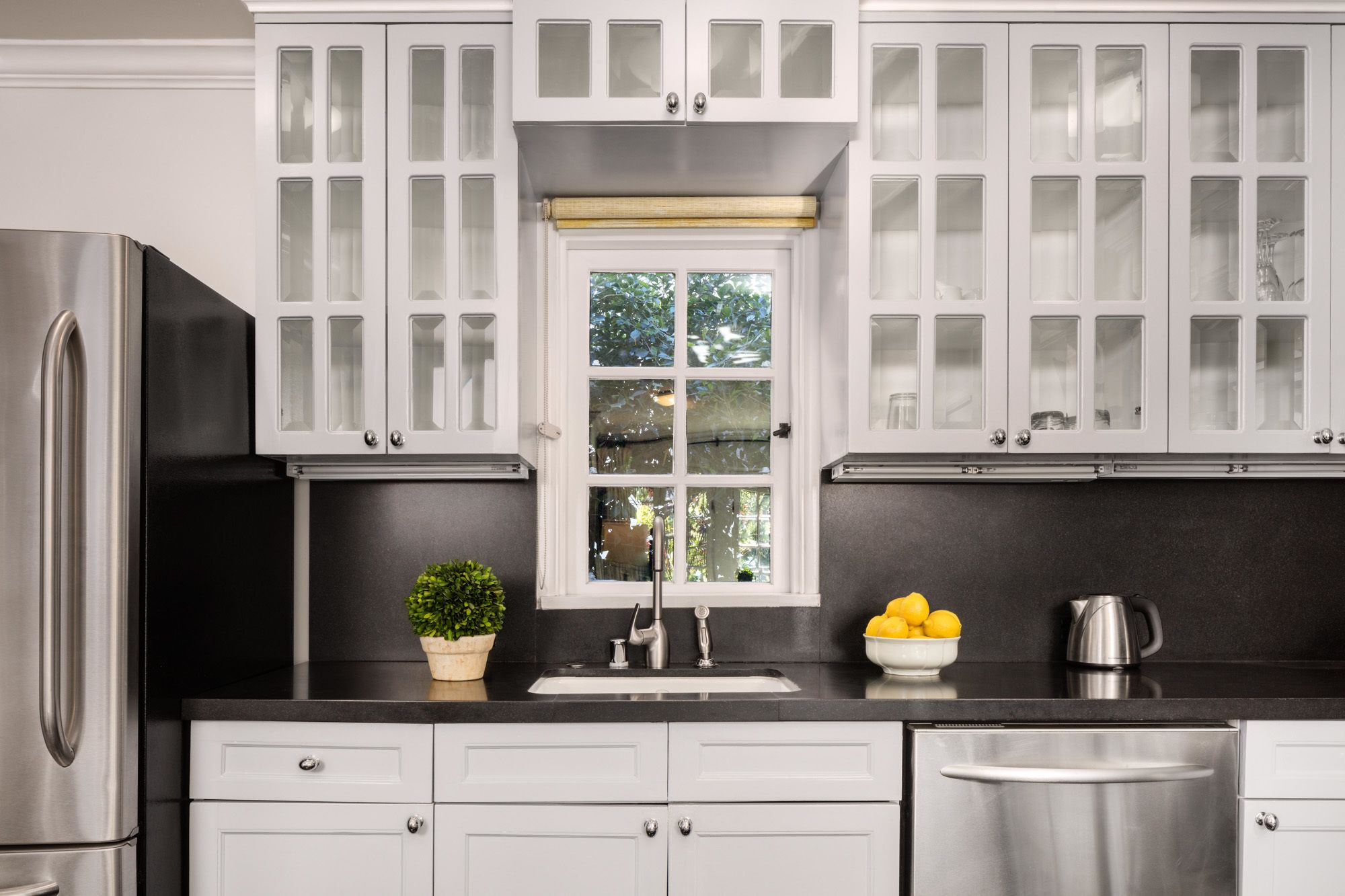 Una cocina moderna con armarios blancos, un refrigerador de acero inoxidable, un lavamanos y un lavavajillas.