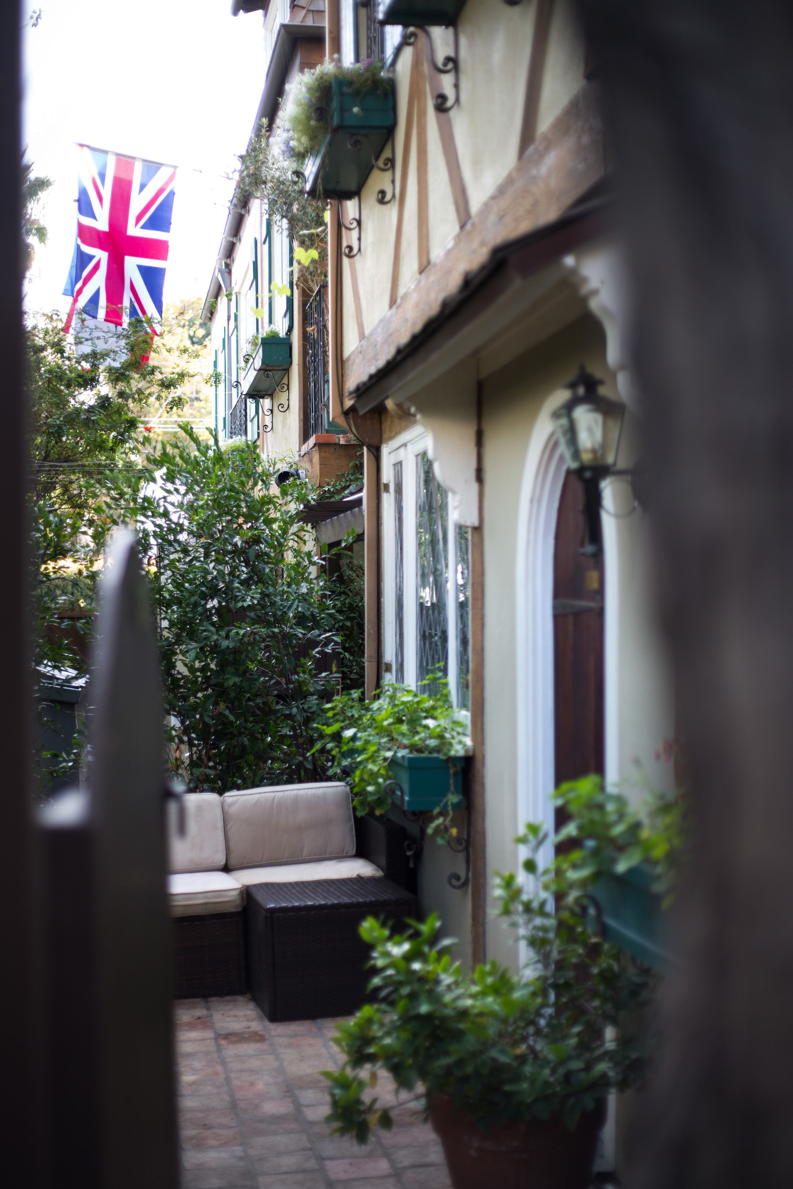 Un estrecho callejón con una bandera británica, un banco y plantas en macetas.