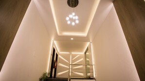 A modern staircase with a geometric light fixture and a glass railing. - Hotel Tropical Daisy (Dhaka)