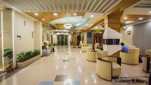 A spacious lobby with a modern design, featuring a central seating area with sofas and a large reception desk. - Hotel Tropical Daisy (Dhaka)