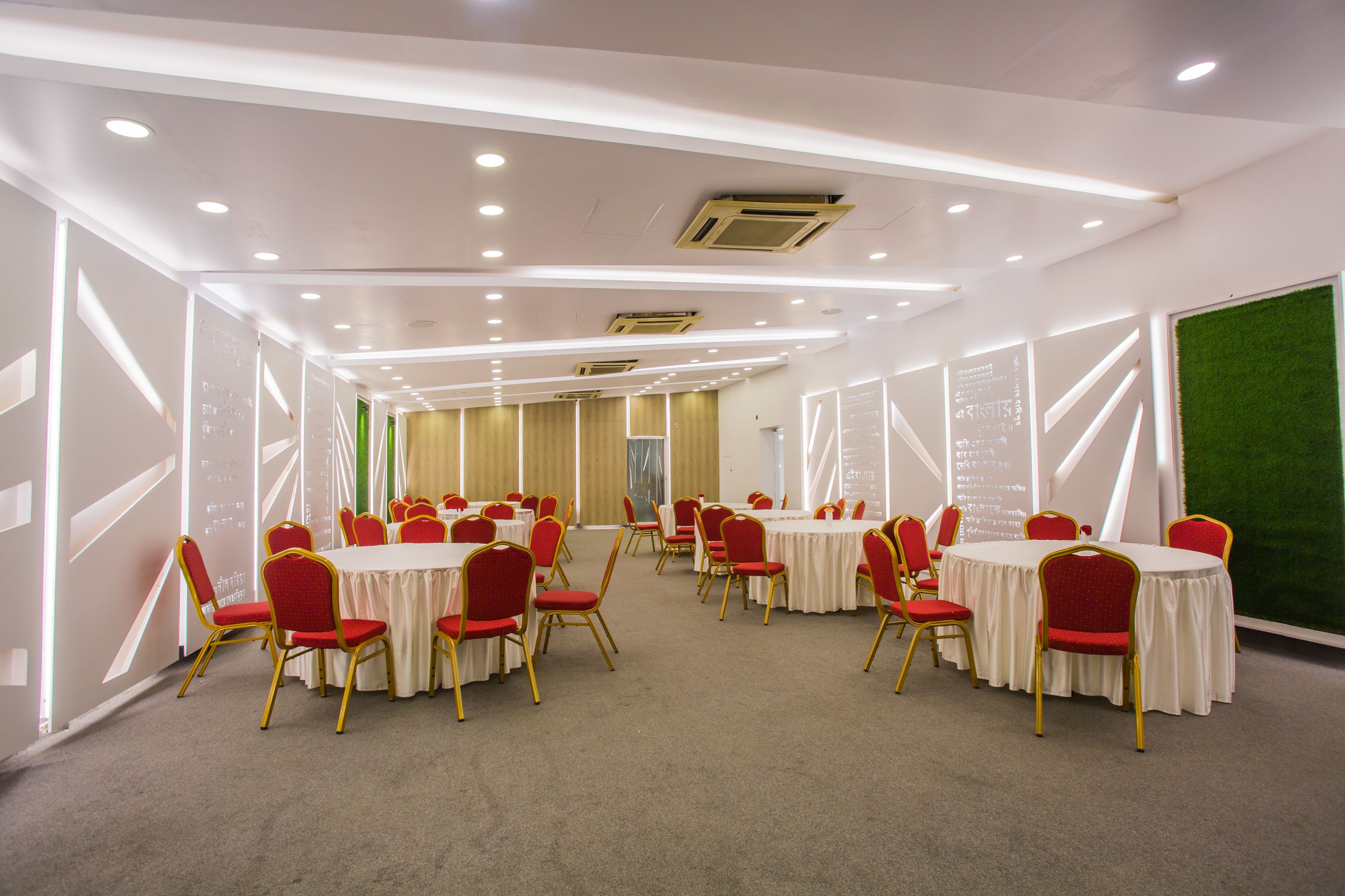 Uma sala de conferências com várias mesas e cadeiras, equipada com iluminação suspensa e unidades de ar condicionado.