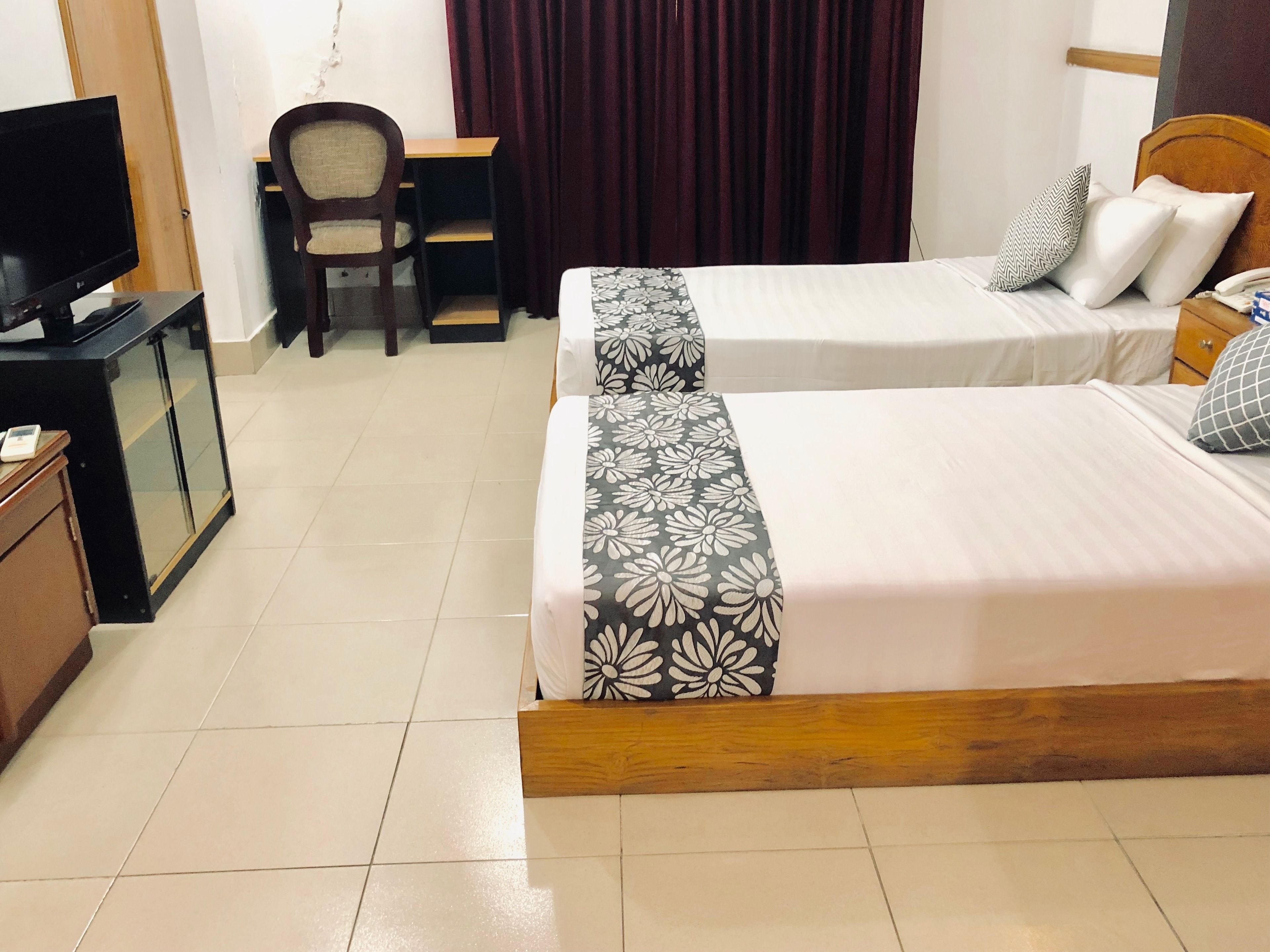 Une chambre d’hôtel avec deux lits, un bureau, une chaise, une télévision et un téléphone.