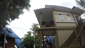 A two-story building with a balcony on the upper floor, a staircase leading to the upper level, and a covered outdoor area with seating. - Moon Beach Resort (Ko Pha-ngan)