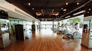 A gym with wooden flooring, exercise equipment, and large windows. - De Richy Chiang Mai (Hang Dong)