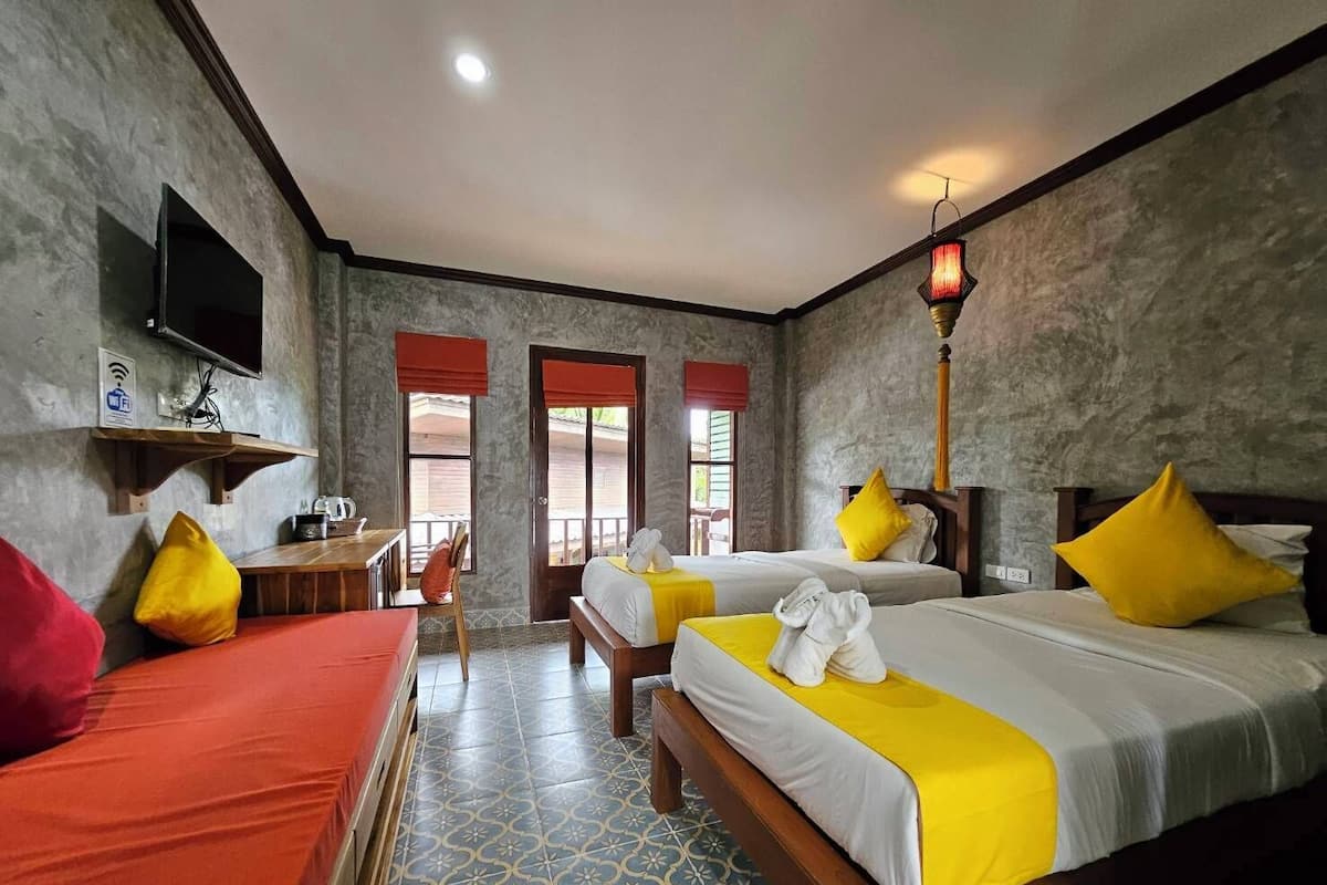 Une chambre d’hôtel avec deux lits, un bureau, une chaise et un téléviseur.
