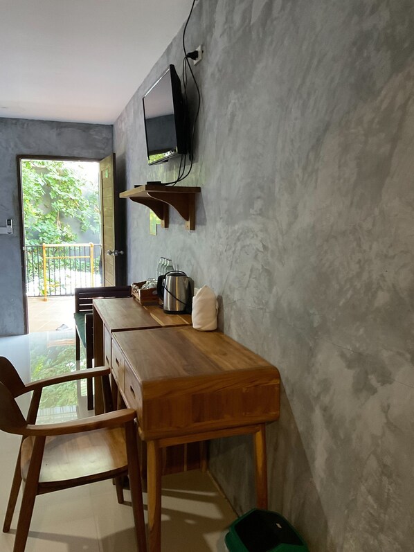 Un comedor con una mesa de madera, sillas, un televisor montado en la pared y vistas al exterior.