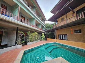 En innergård med en swimmingpool, ett takförsett område och en byggnad med balkonger.