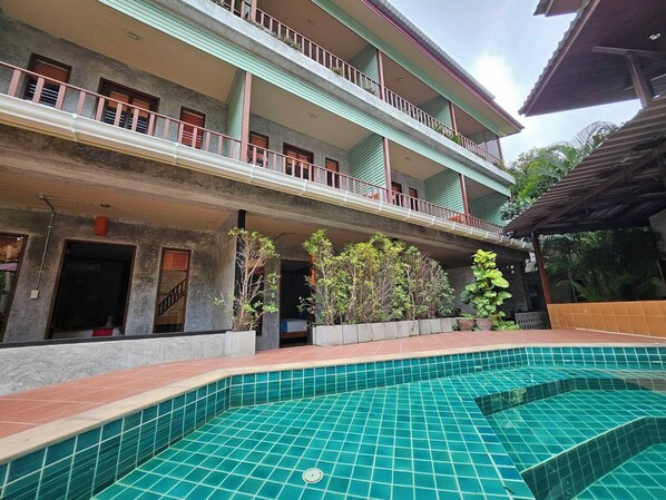 Un hôtel doté d’une piscine, de plusieurs balcons et de plantes en pot.