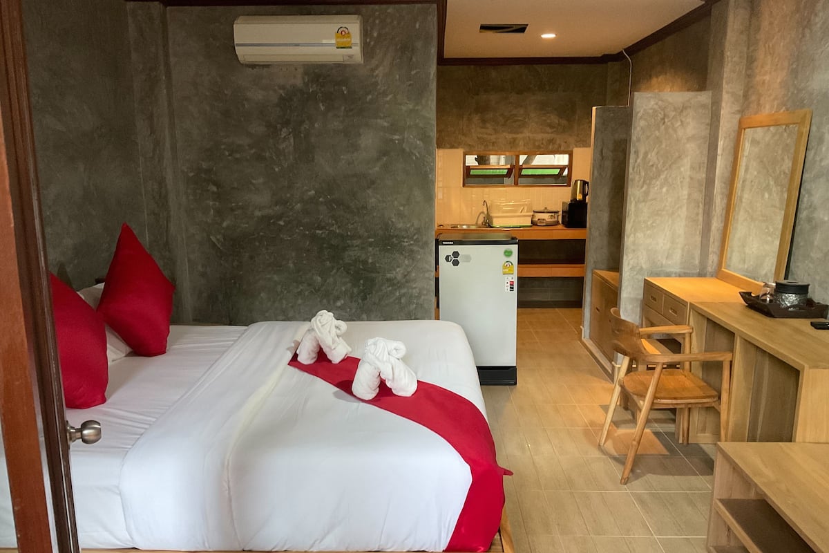Une chambre d’hôtel équipée d’un lit, d’un bureau, d’un réfrigérateur et d’un miroir.
