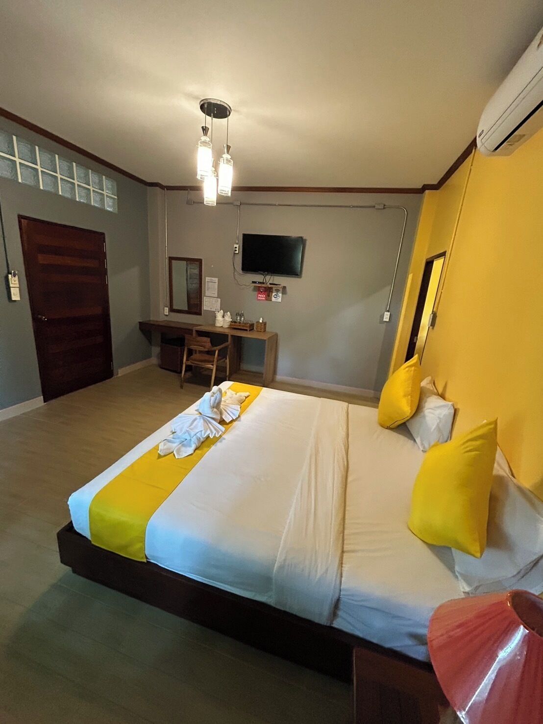 Una habitación de hotel con una cama, un escritorio, un televisor y una ventana.