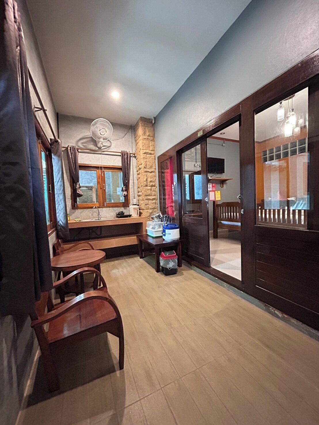 Una habitación con comedor, un pilar de piedra, un ventilador, una ventana con cortinas y vistas al exterior.