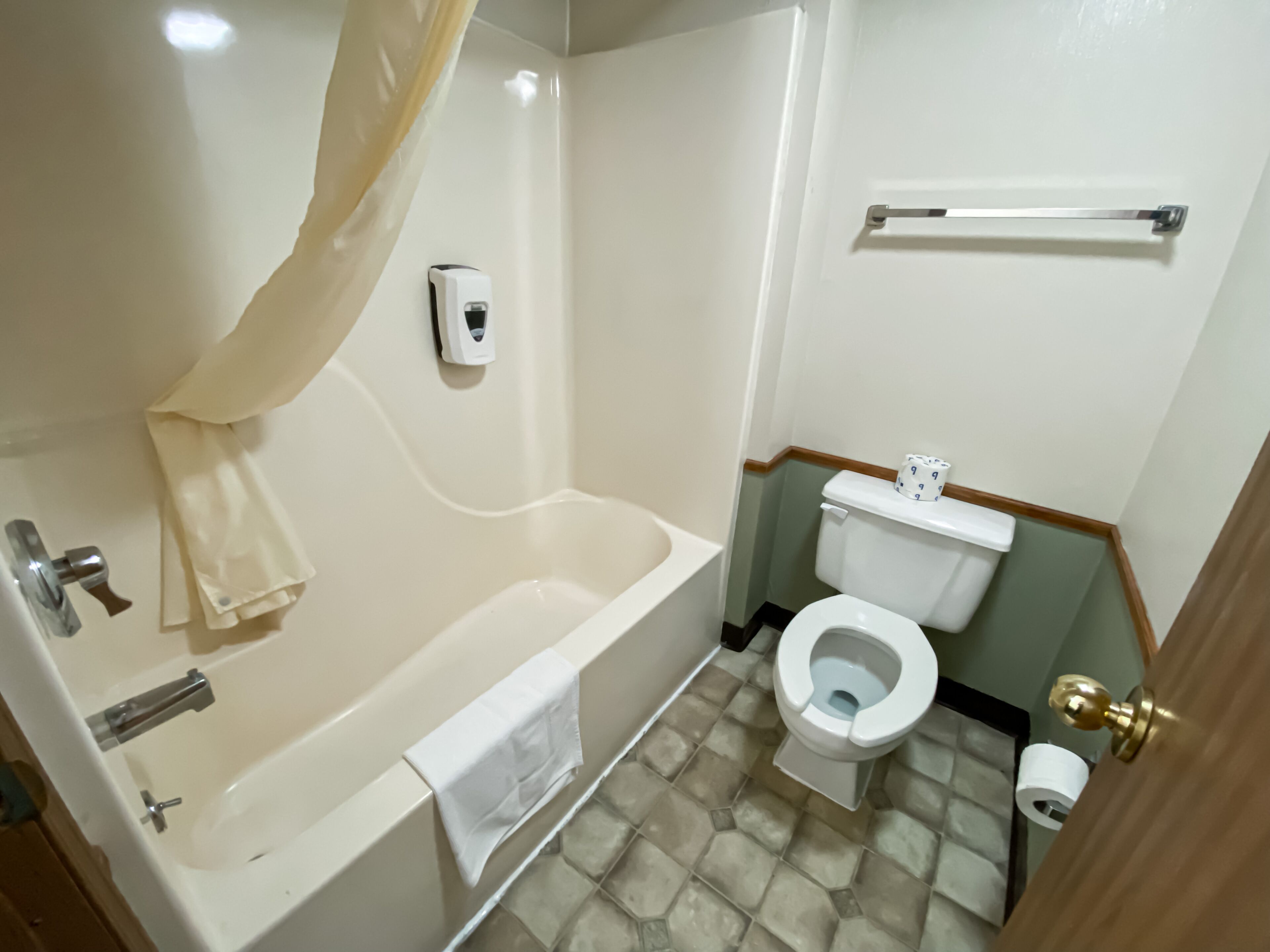 A bathroom with a bathtub, toilet, and hand dryer.