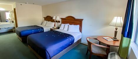 Une chambre d’hôtel avec deux lits, une petite table avec une chaise, une lampe et une fenêtre avec des rideaux.