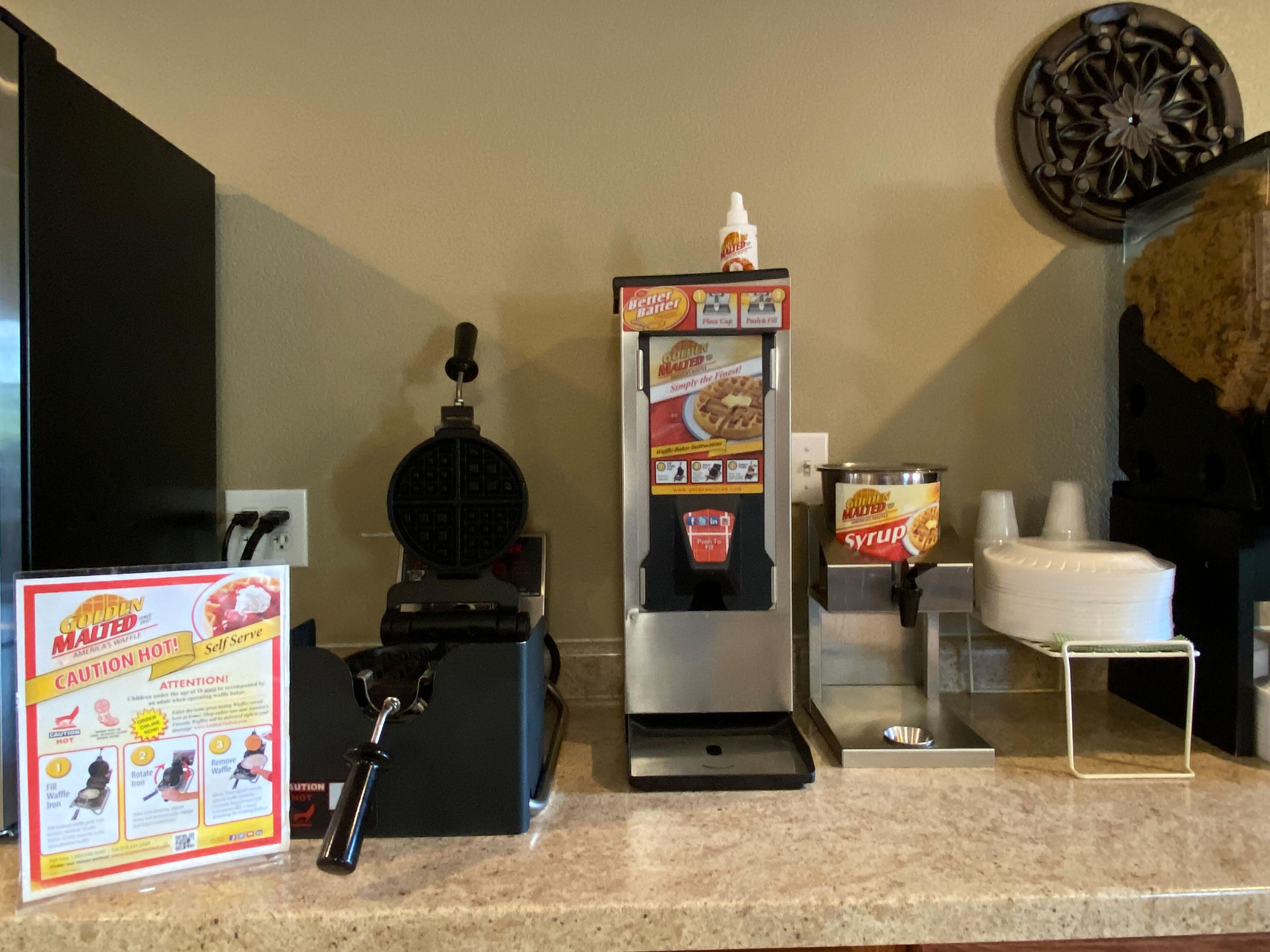Un espace en libre-service où l’on peut préparer des gaufres, avec un distributeur de sirop et un bouton-poussoir pour lancer la cuisson des gaufres.