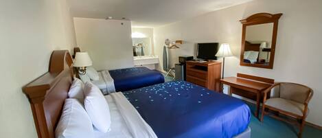 A hotel room with two beds, a desk, a chair, a TV, and a mirror.