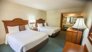 A hotel room with two beds, a desk, a chair, a lamp, a telephone, and a mirror. - Green Gables Inn (Branson)