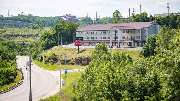 A hotel with a red roof, multiple windows, and a signboard with "Welcome" visible. - Rosebud Inn (Branson)