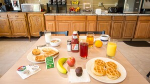 A breakfast table with waffles, toast, a muffin, a banana, an apple, and various condiments. - Rosebud Inn (Branson)