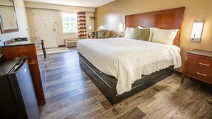 A hotel room with a large bed, a dresser, a chair, and a desk. - Rosebud Inn (Branson)