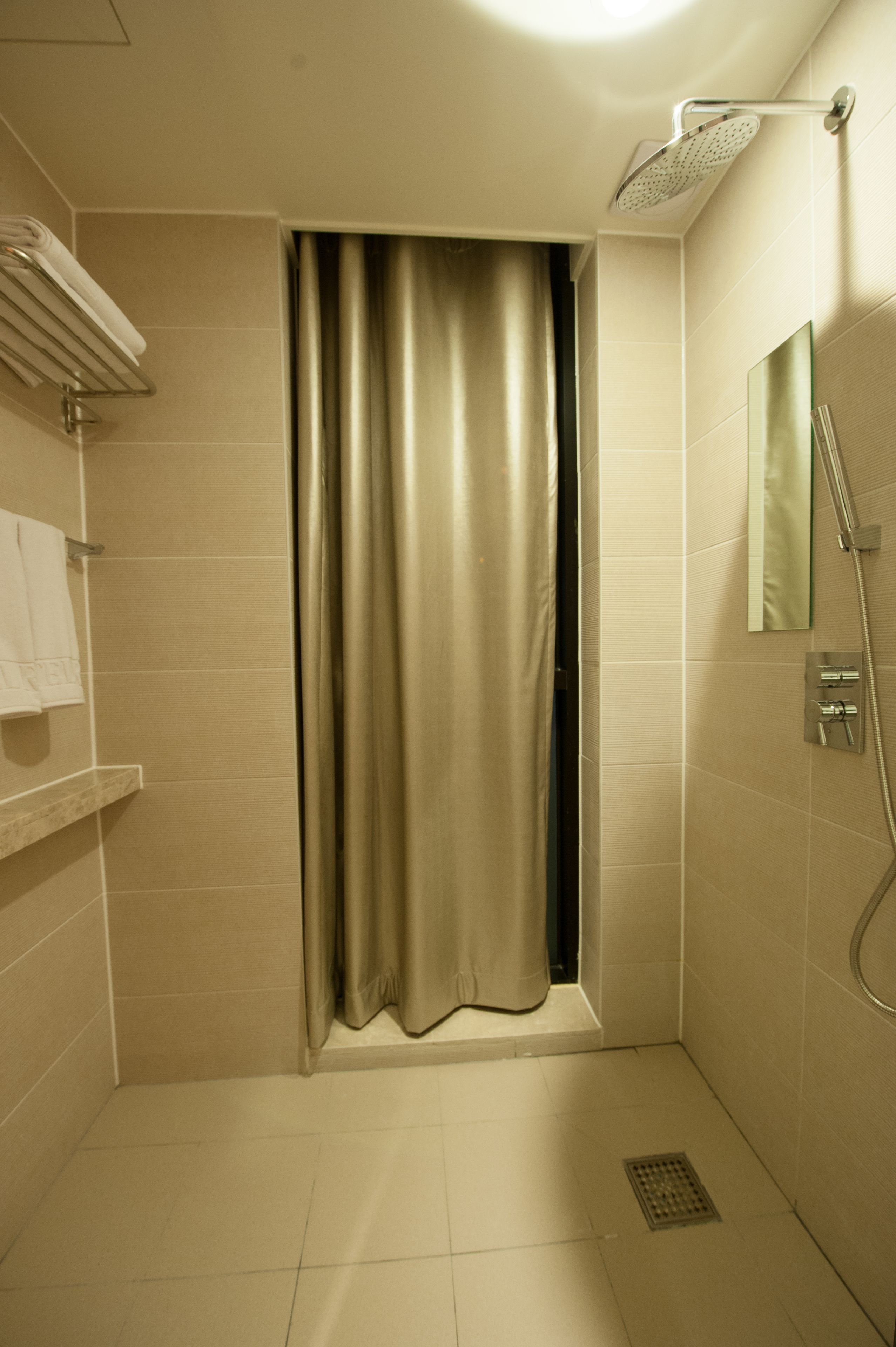 A modern bathroom with a shower, a towel rack, and a mirror.