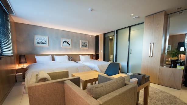 A modern hotel room with a large bed, two bedside tables, a desk, a chair, and a kitchenette. - Hotel Rian (Seoul)