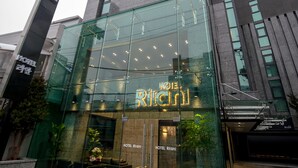 A modern hotel with a glass facade, a visible lobby area with seating, and a prominent sign. - Hotel Rian (Seoul)