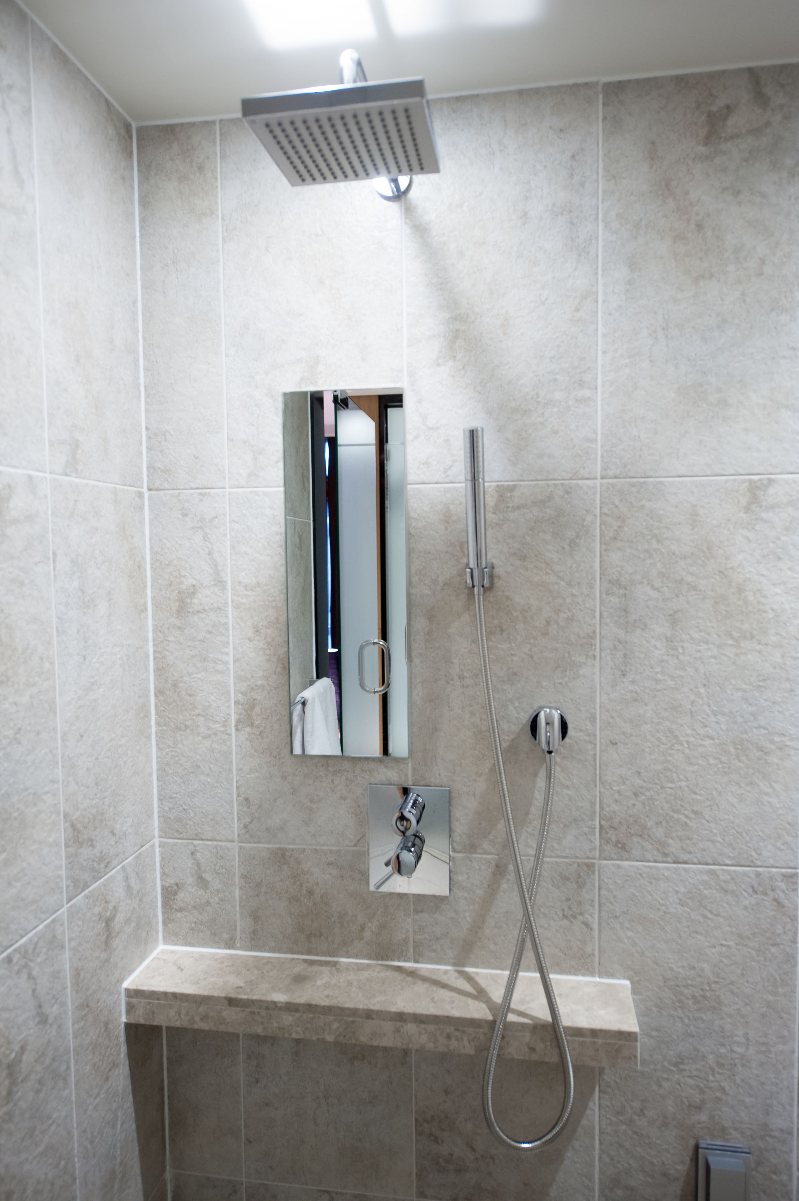 Une salle de bain avec une douche, un miroir et un porte-serviettes.