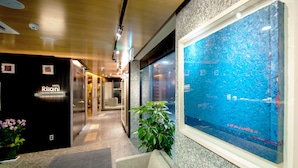 A hotel lobby with a reception desk, a plant, and a large window with a view. - Hotel Rian (Seoul)