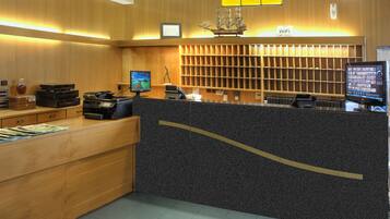 A hotel reception area with a wooden counter, two monitors, a ship model, and a WiFi sign.