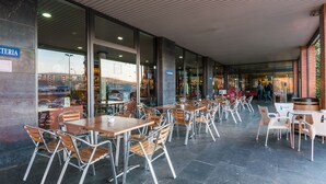 An outdoor café with tables and chairs, a brick wall, and a sign reading "Cafeteria". - Hotel Ruta de Europa (Vitoria-Gasteiz)