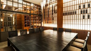 A spacious conference room with a long table and chairs, a wine rack on the wall, and a staircase leading to an upper level. - Hotel Ruta de Europa (Vitoria-Gasteiz)