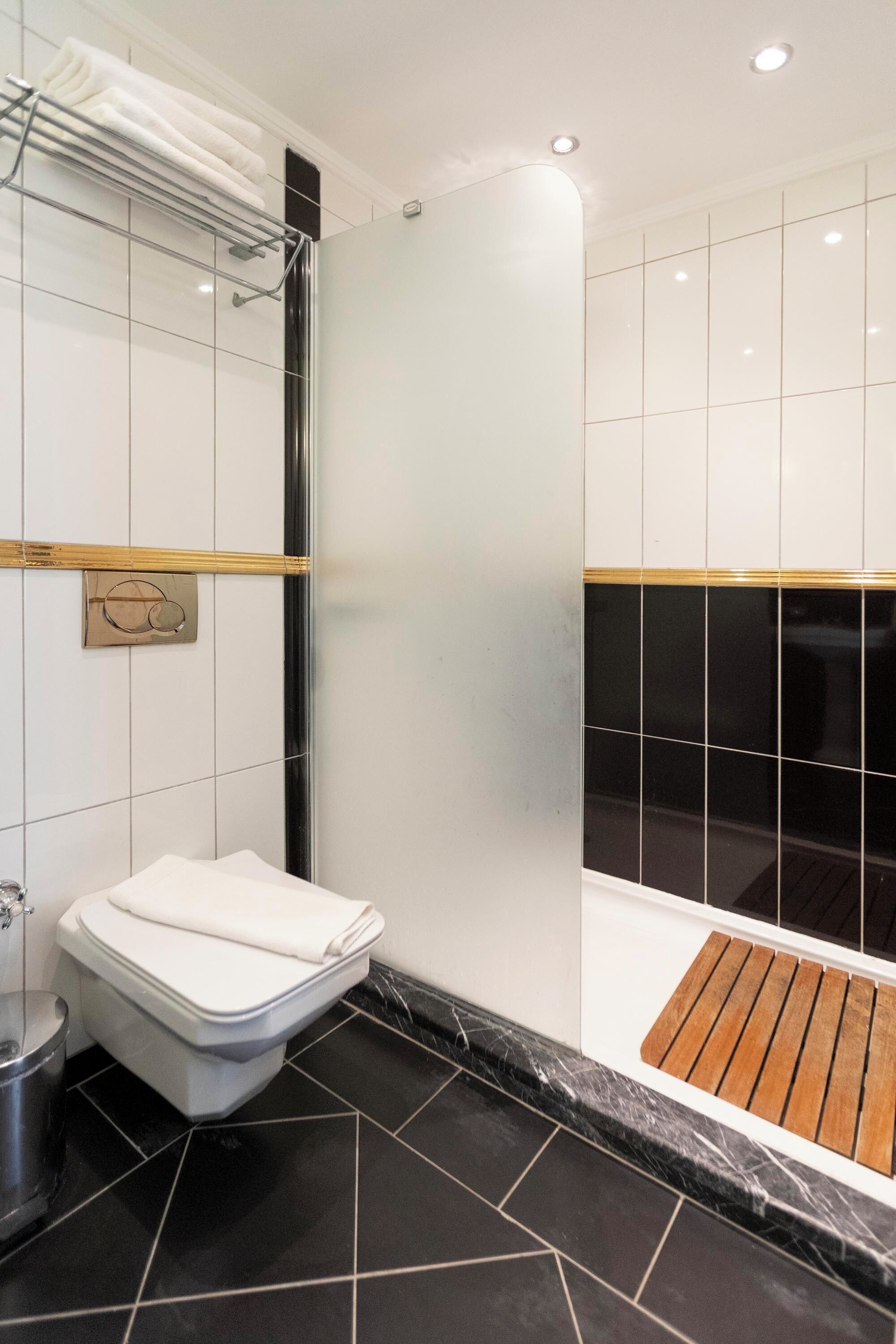 A modern bathroom with a shower, toilet, and a towel rack.