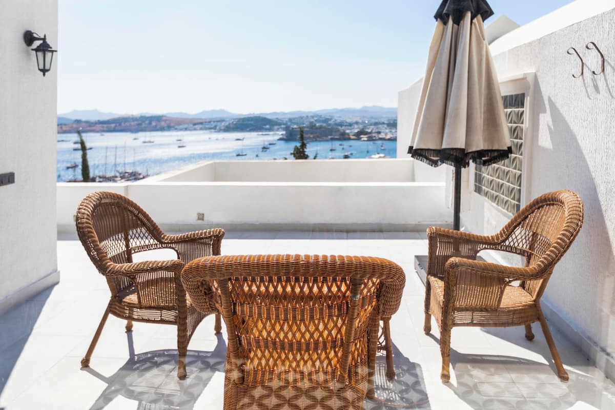 A balcony with wicker furniture and a view of the sea.
