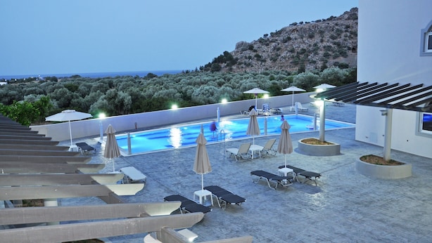 A rooftop pool area with lounge chairs and umbrellas, overlooking a mountainous landscape. - Daniel Luxury Apartments (Rhodes)